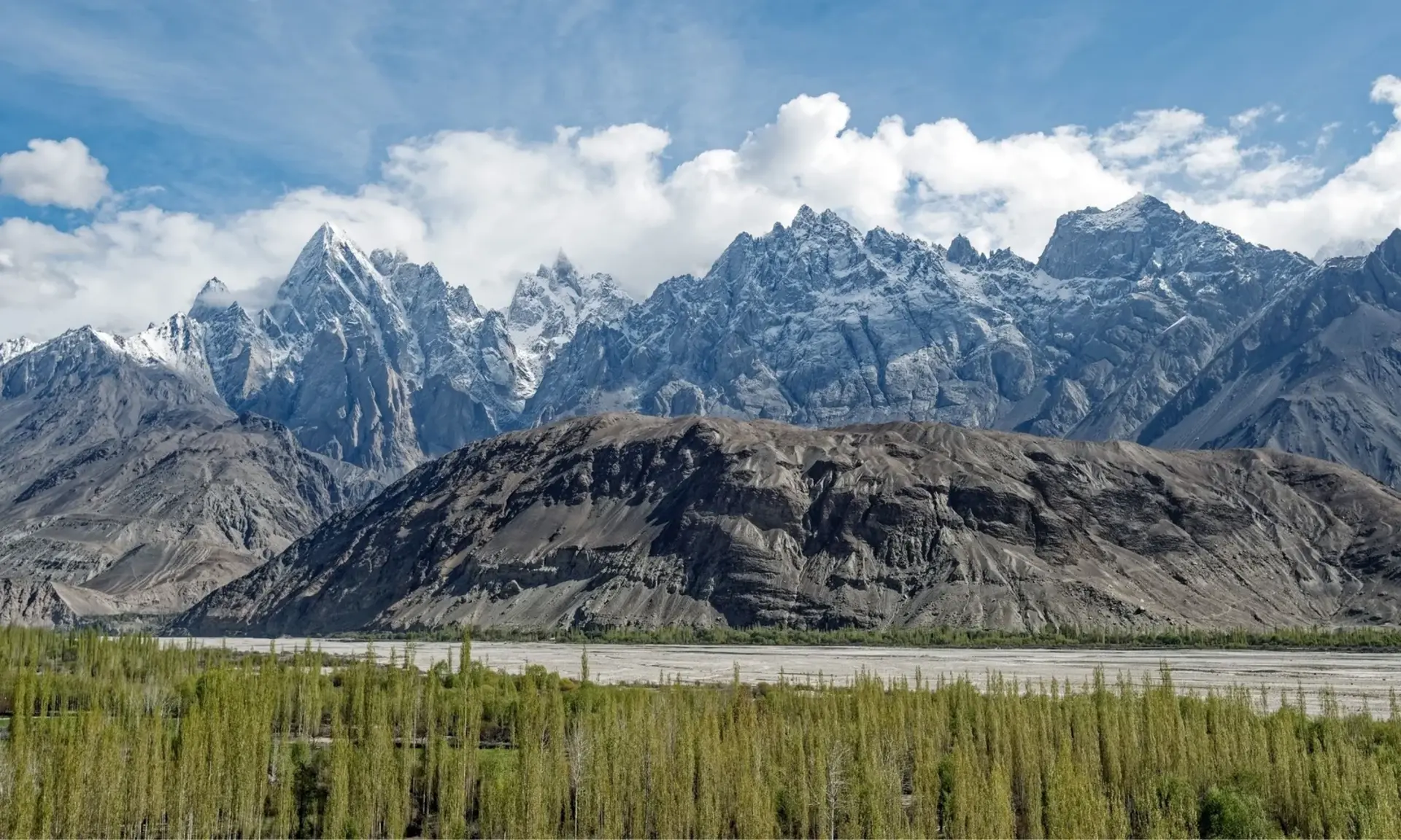 Snow-capped mountains above green fields near Gilgit, Pakistan