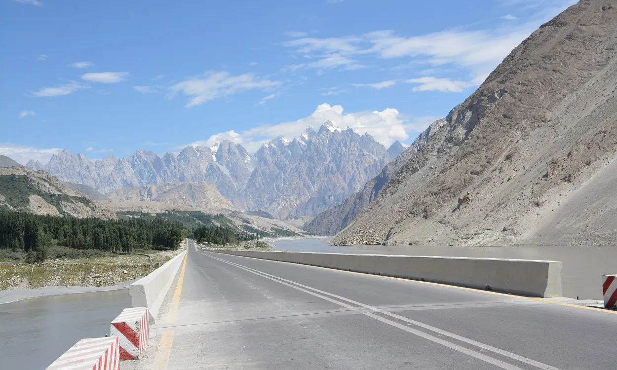 The Karakoram Highway running beside the Hunza River towards snowy peaks, Pakistan
