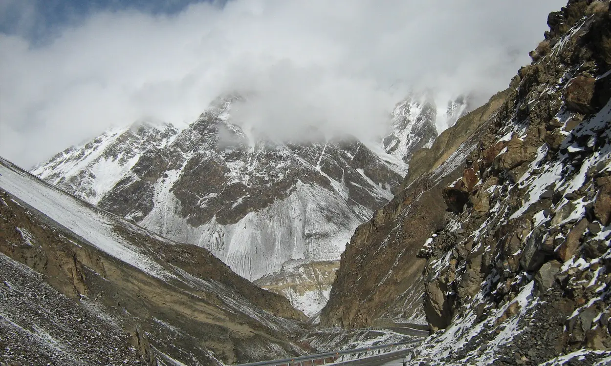The Karakoram Highway winding below snowy peaks near the Khunjerab Pass, Pakistan