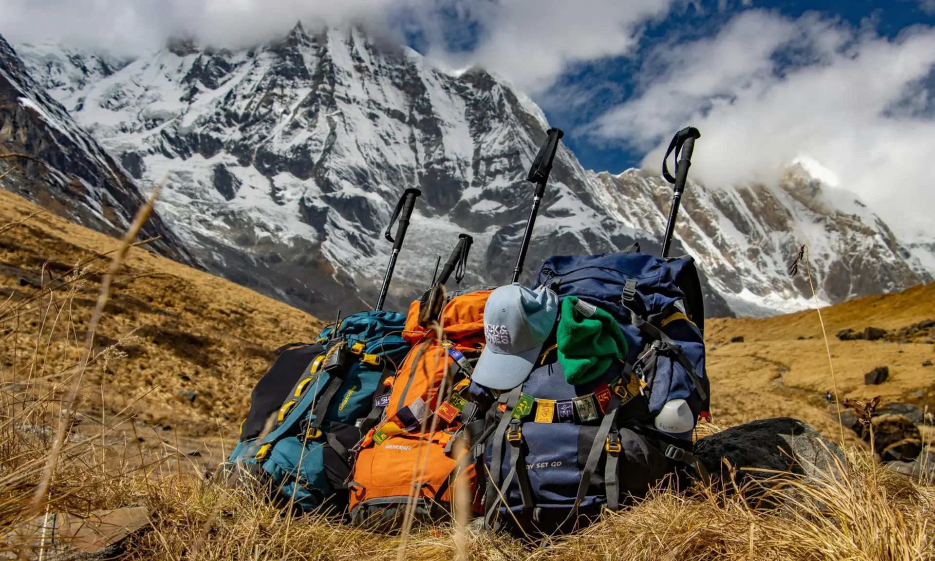 Trekking backpacks and poles below snowy peaks, trekking gear guide for Pakistan
